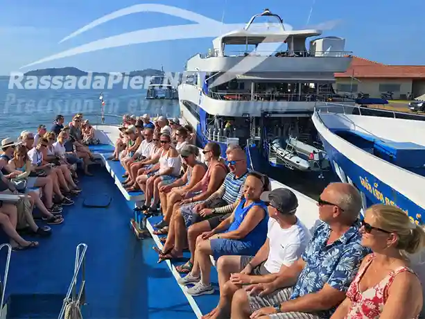 Passengers relaxing on the open top deck of a large Phuket ferry docked at the Phuket Ferry Terminal before departure.